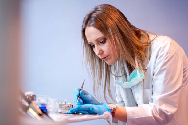 Denturist closely examining dental equipment