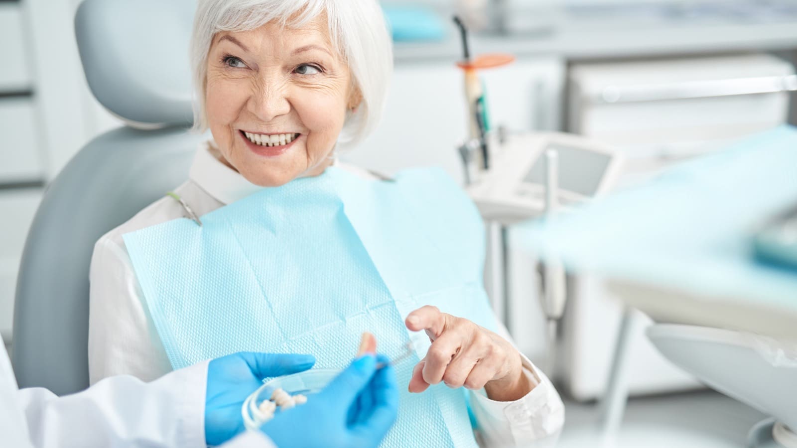 Elderly woman in dentist chair looking at dentures