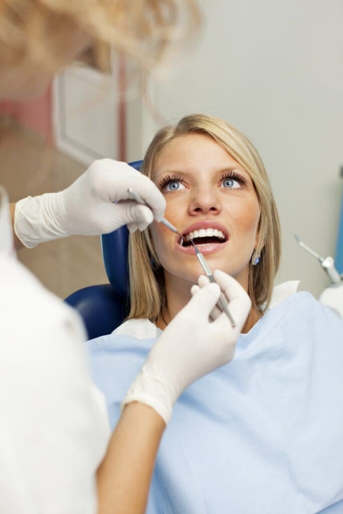 Portrait of an cute smiling teenage girl having consultations with her dentist at dentist office. Dentist is doing dental filling to patient.