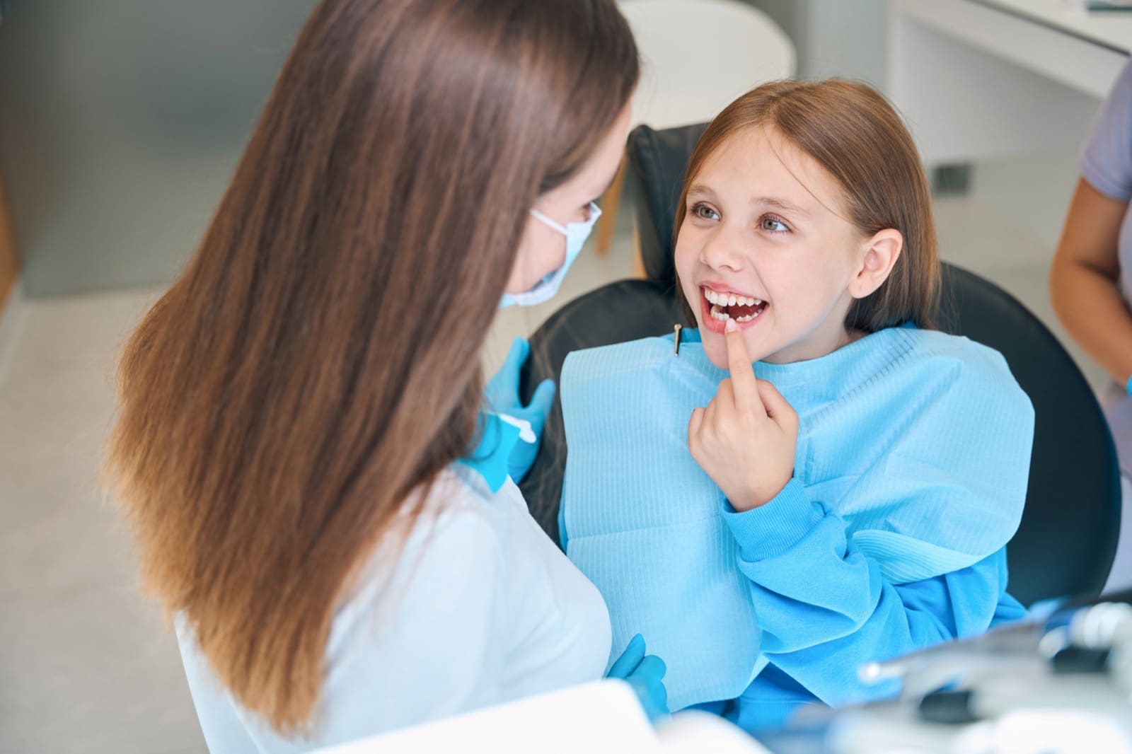 Girl shows her teeth to a woman a dentist, a doctor in a protective mask and gloves