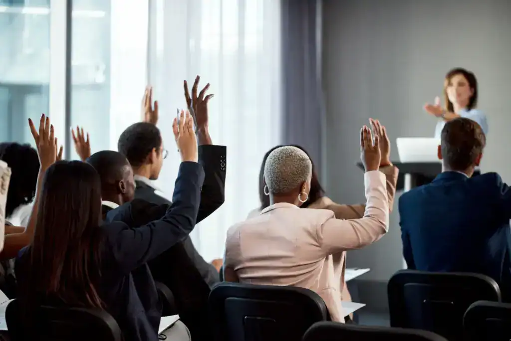 Group of people at conference raising their hands